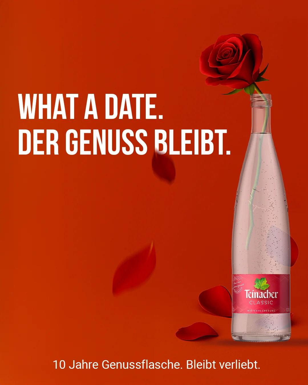 Teinacher-Kampagnenmotiv 'What a date – der Genuss bleibt': rote Rose im Flaschenhals einer Teinacher Classic, umgeben von fallenden Rosenblättern, vor rotem Hintergrund