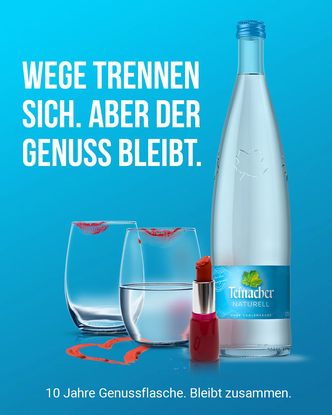 Teinacher-Kampagnenmotiv 'Wege trennen sich – aber der Genuss bleibt': zwei Trinkgläser mit Lippenstiftabdruck und ein durchgestrichenes, aufgemaltes Herz neben einer Flasche Teinacher Naturell vor blauem Hintergrund