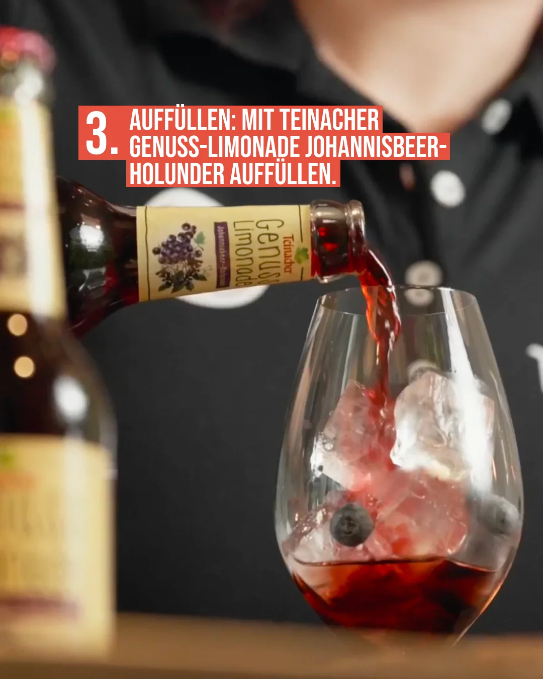 Cocktail-Rezept Schritt 3: Teinacher-Mitarbeiter (nur Ausschnitt sichtbar) füllt ein mit Eis und Blaubeeren gefülltes Glas mit Teinacher Genuss-Limonade Johannisbeer-Holunder auf
