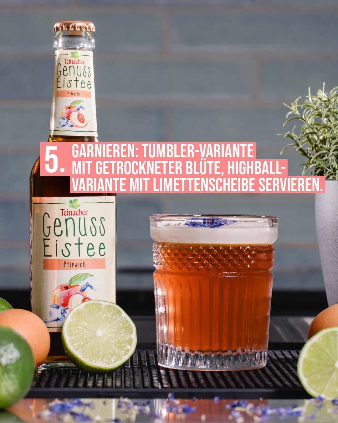 Cocktail-Rezept Schritt 5: Teinacher Genuss Eistee Pfirsich neben einem Tumbler-Glas mit Pfirsich-Cocktail, garniert mit getrockneter Blüte, umgeben von Limetten und Eiern